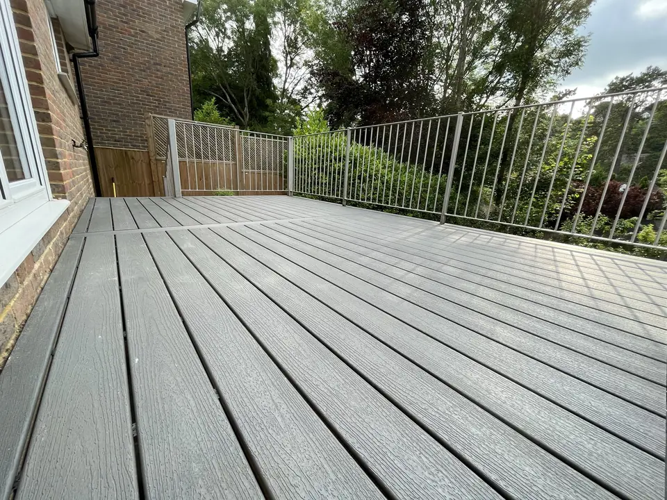 Grey composite deck boards running to a steel balustrade, with trees beyond