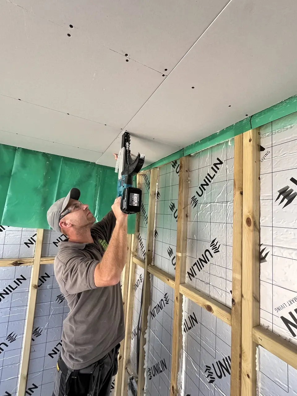Jon fixing a board inside an insulated timber frame