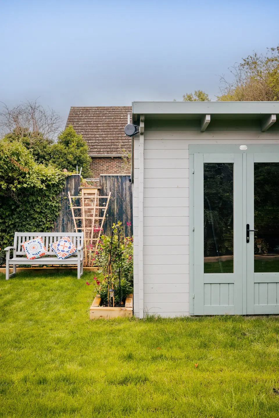 Glazed double doors on the sage log cabin, opening onto the lawn