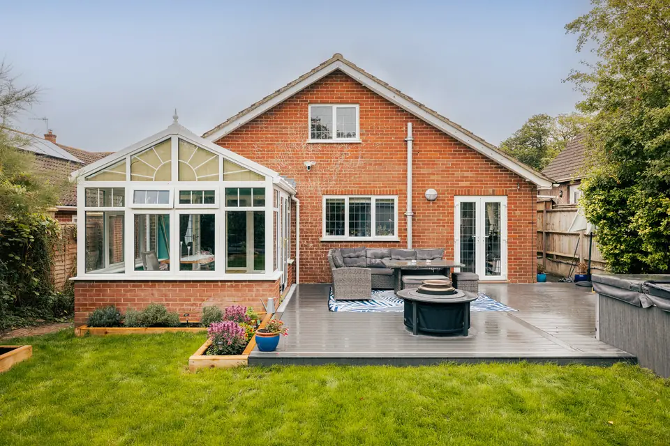 Composite deck laid across the back of the house, with seating, a fire pit and raised beds