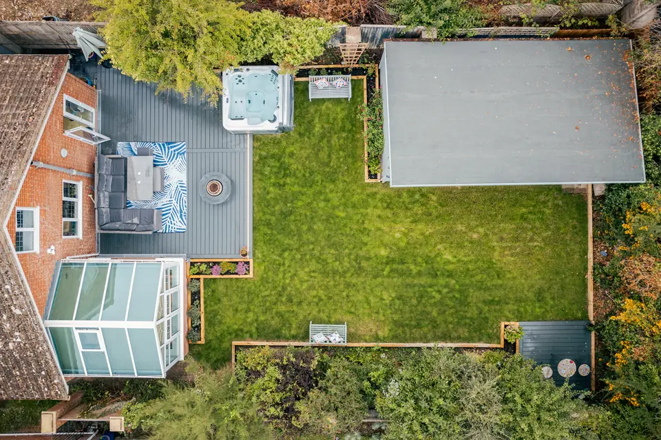 Aerial view of the whole garden: deck by the house, lawn framed by raised beds and the cabin at the end