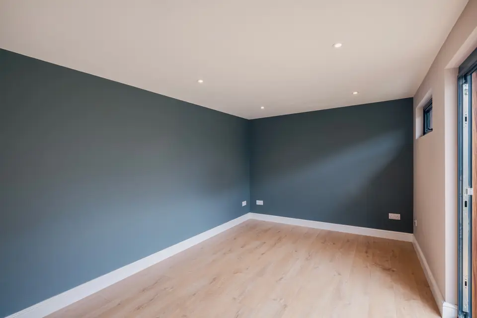 Empty garden studio interior with painted walls, skirting, sockets and a slim high window